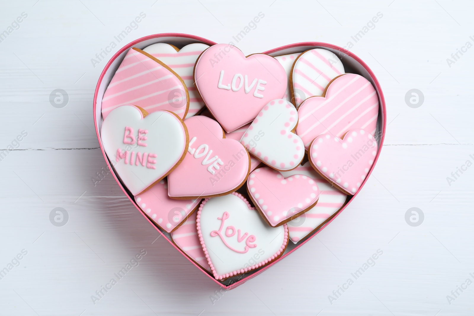 Photo of Delicious heart shaped cookies in box on white wooden table, top view. Valentine's Day