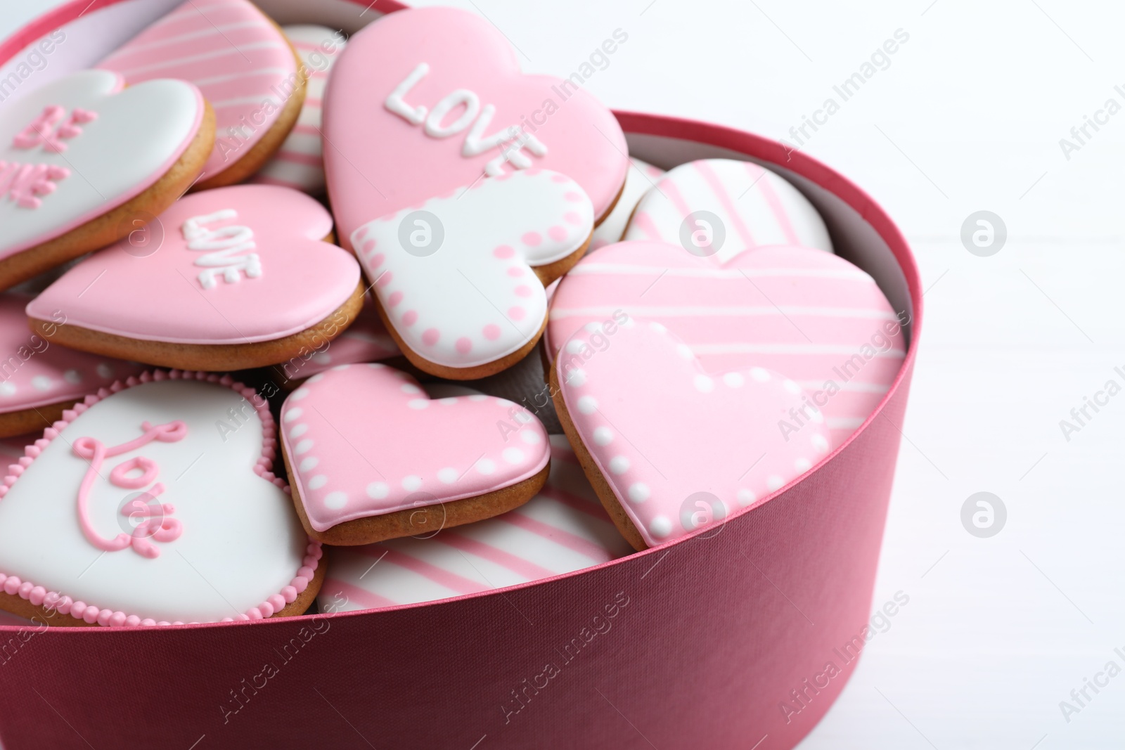 Photo of Delicious heart shaped cookies in box on white table, closeup. Valentine's Day