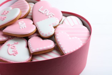 Photo of Delicious heart shaped cookies in box on white table, closeup. Valentine's Day