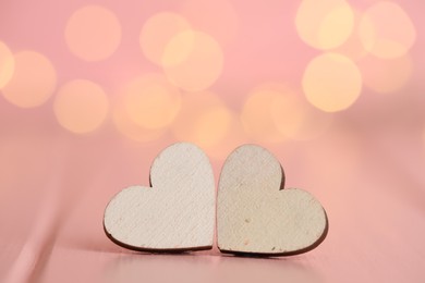 Photo of White hearts on wooden table against festive lights, space for text. St. Valentine's day