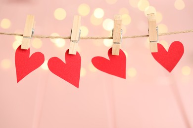 Photo of Red hearts hanging on rope against festive lights. St. Valentine's day