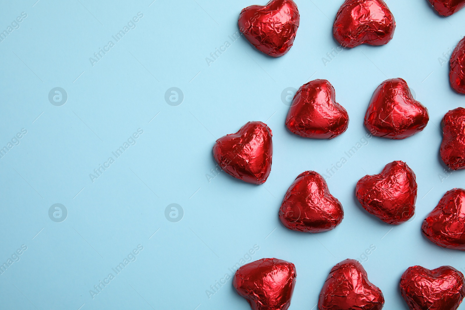 Photo of Heart shaped chocolate candies on light blue background, flat lay with space for text. Valentine's day treat