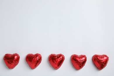 Photo of Heart shaped chocolate candies on white background, flat lay with space for text. Valentine's day treat