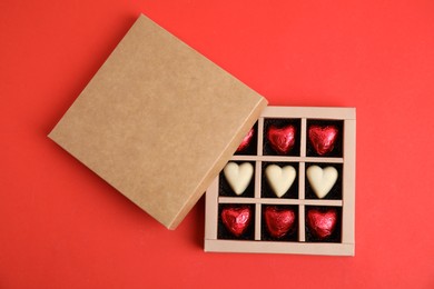 Photo of Tasty heart shaped chocolate candies on red background, flat lay. Happy Valentine's day