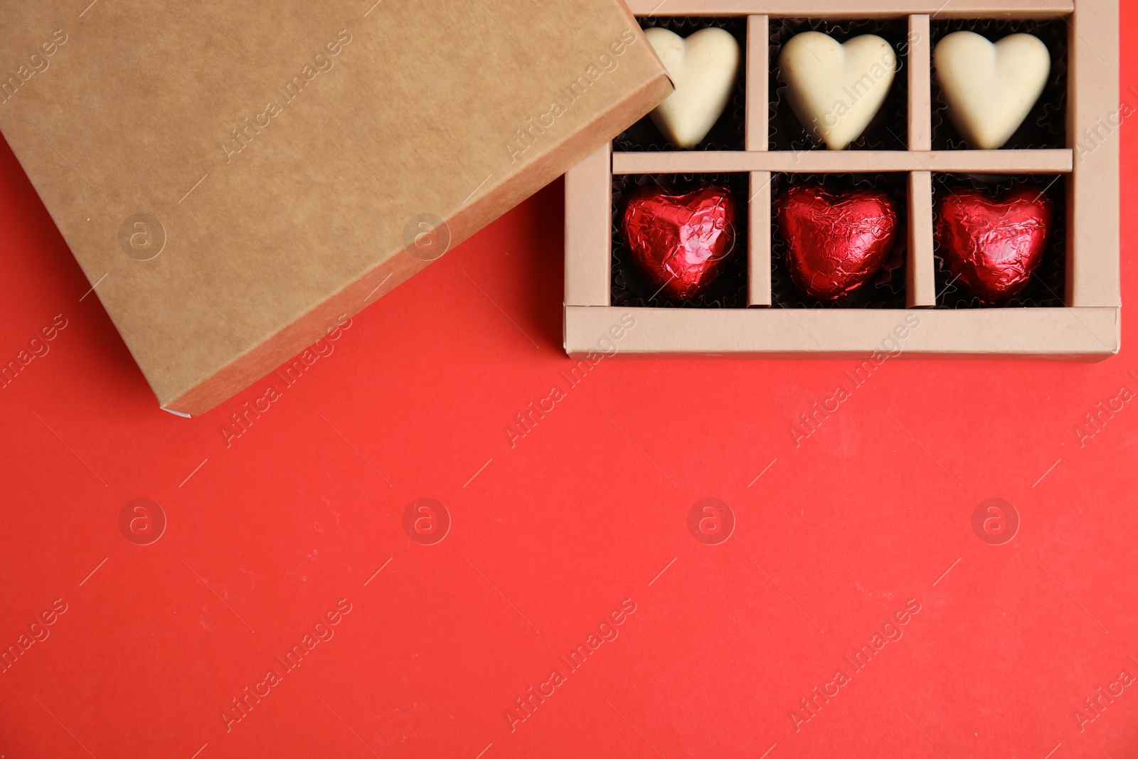 Photo of Tasty heart shaped chocolate candies on red background, flat lay with space for text. Happy Valentine's day