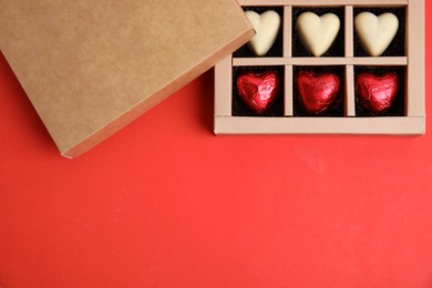 Photo of Tasty heart shaped chocolate candies on red background, flat lay with space for text. Happy Valentine's day