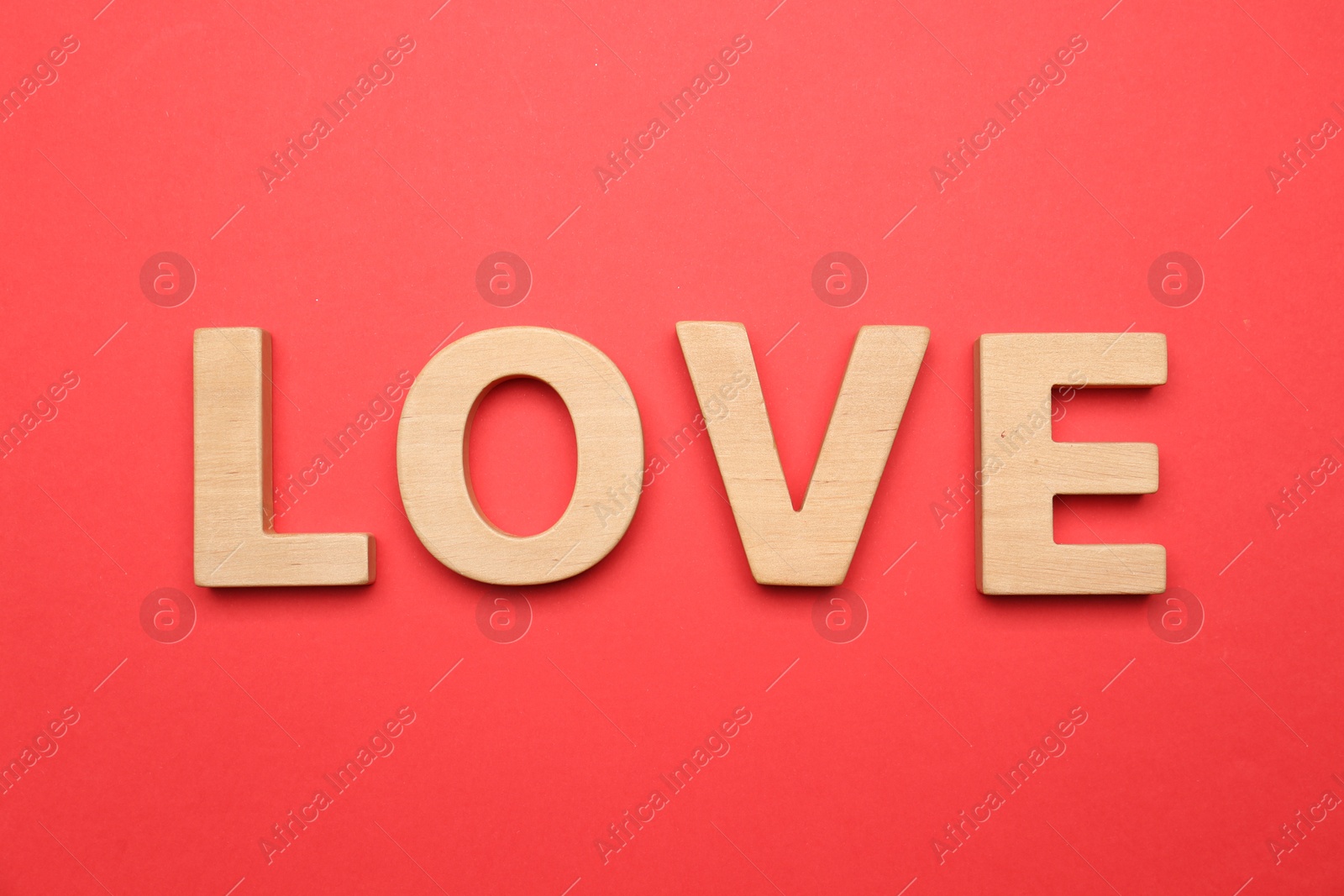 Photo of Word LOVE made of wooden letters on red background, flat lay