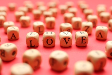 Photo of Mini cubes with letters forming word Love on red background, closeup