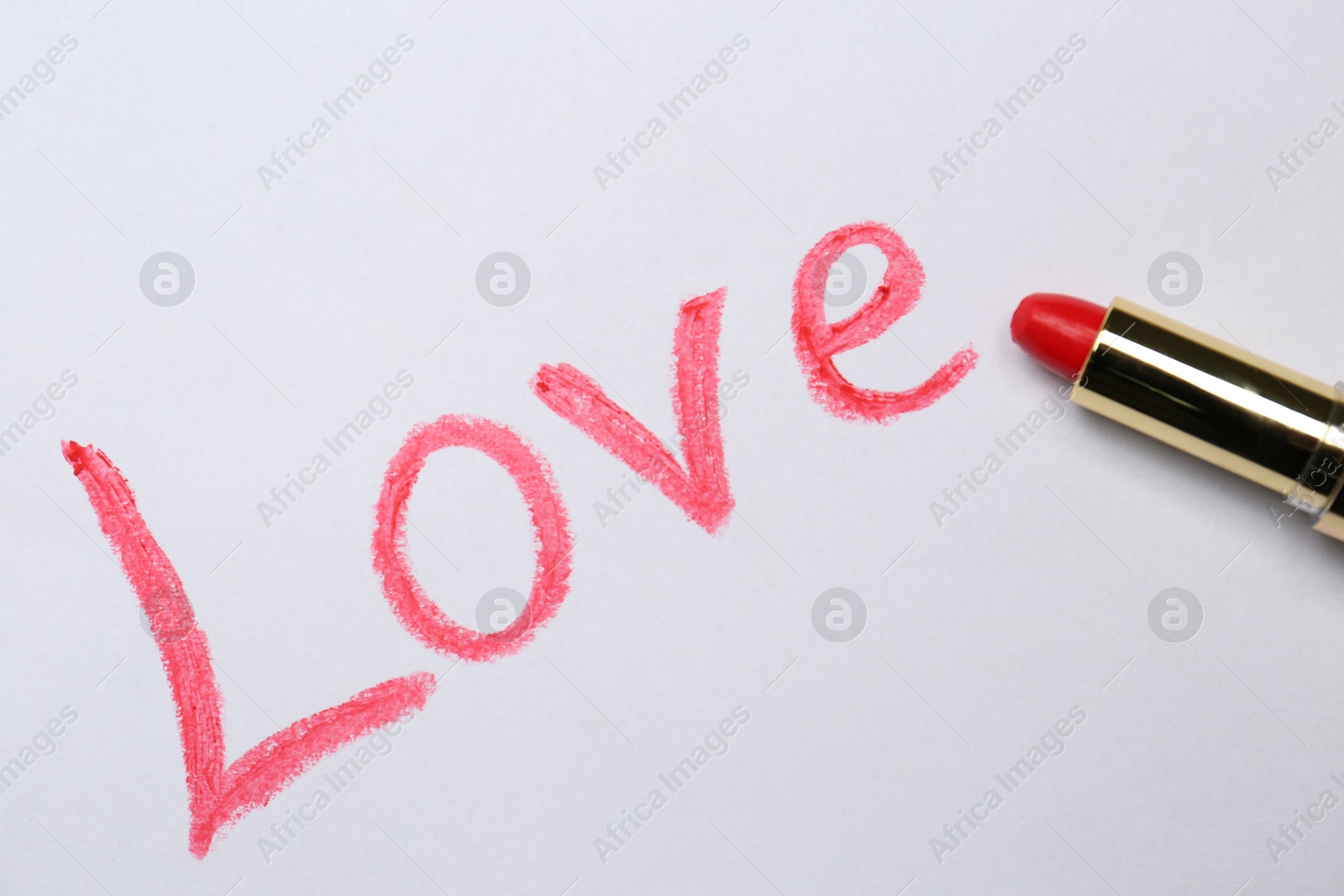 Photo of Word LOVE written with lipstick on white background, top view