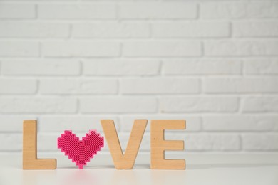 Photo of Word Love made of wooden letters and decorative heart on white table. Space for text