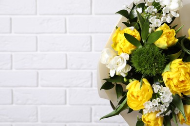 Photo of Beautiful bouquet with peony tulips near white brick wall, closeup. Space for text