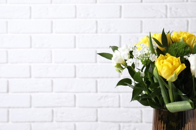 Photo of Beautiful bouquet with peony tulips near white brick wall, closeup. Space for text