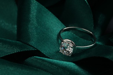 Photo of Beautiful luxury engagement ring with gemstone on green ribbon, closeup