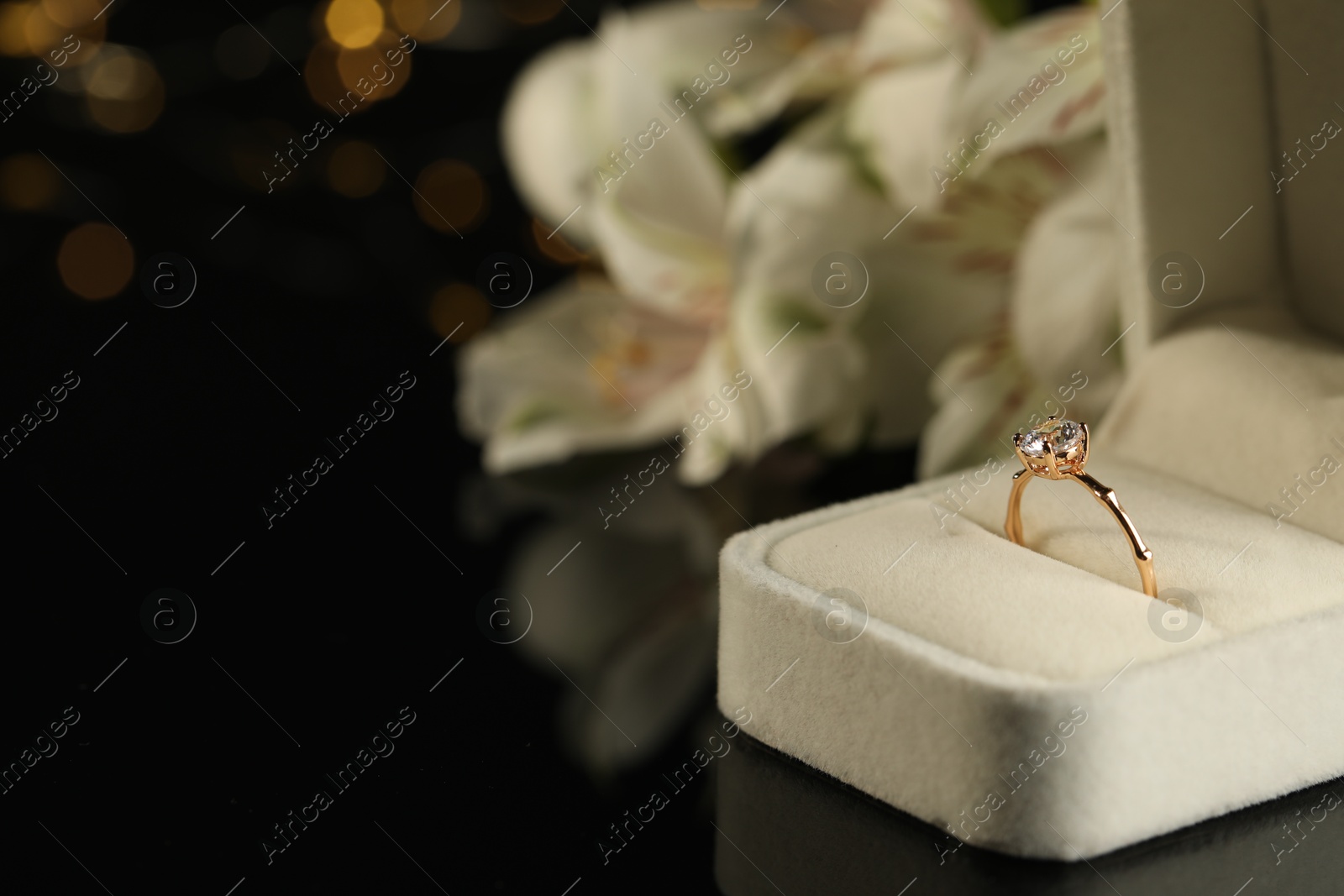 Photo of Beautiful engagement ring in box against blurred background, space for text