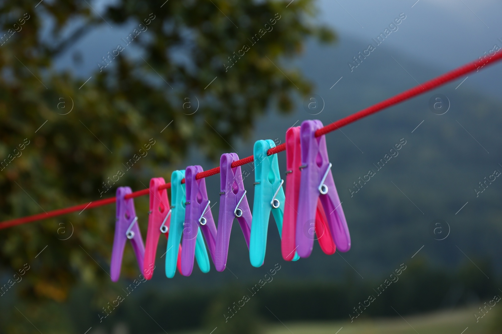 Photo of Colorful clothespins hanging on washing line outdoors