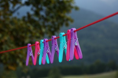 Photo of Colorful clothespins hanging on washing line outdoors