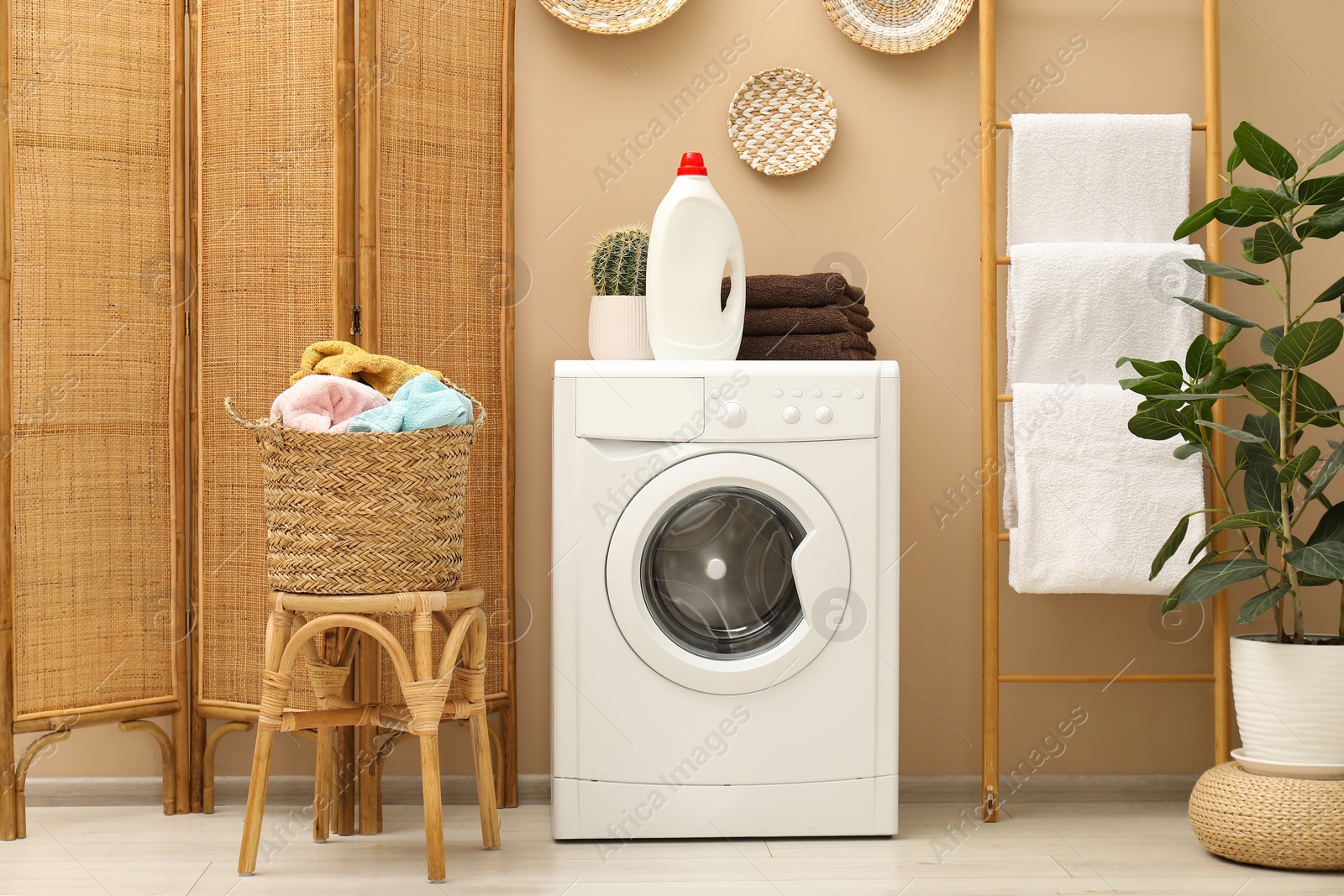 Photo of Wicker basket full of laundry, washing machine and detergent in bathroom