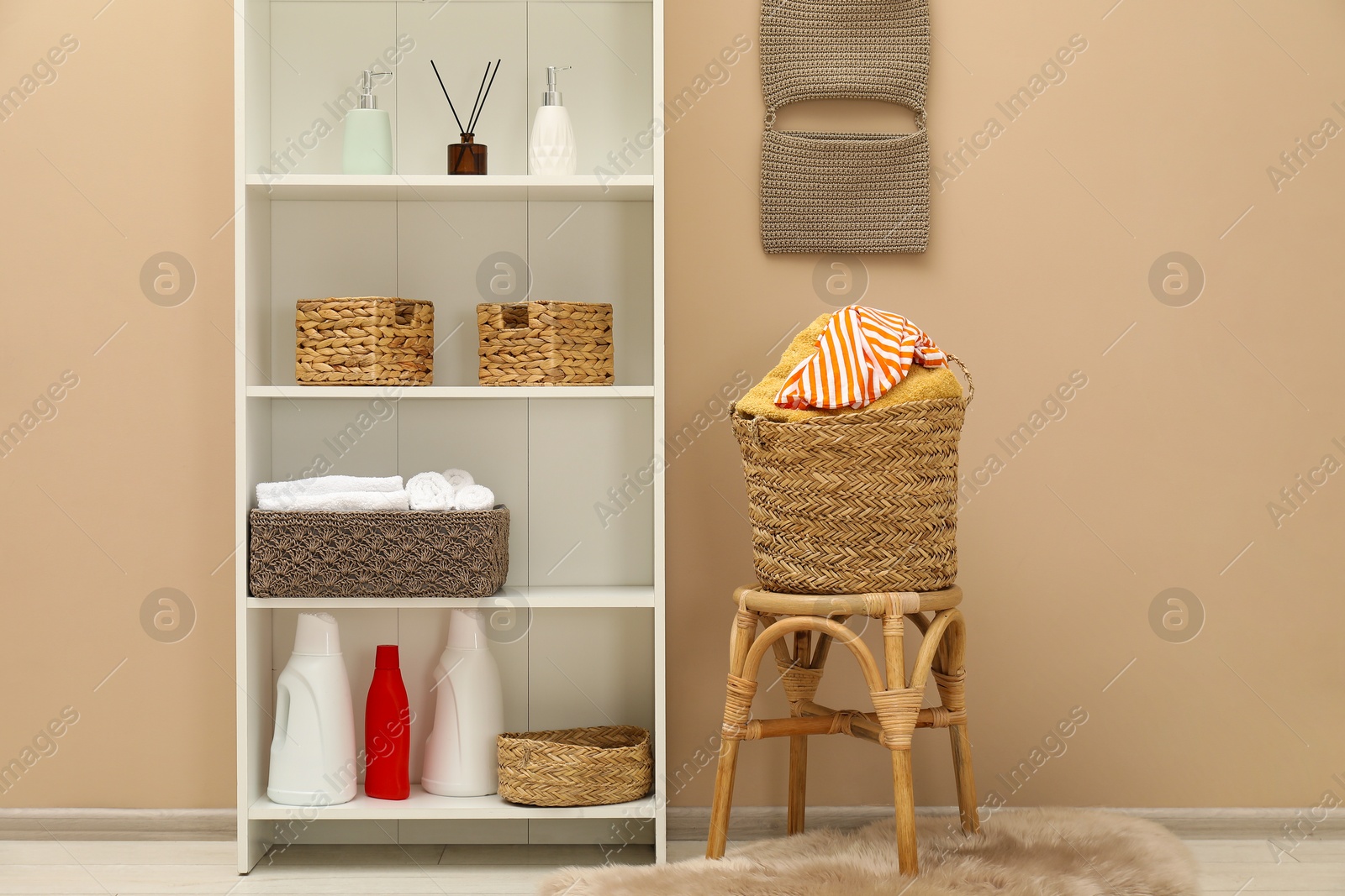 Photo of Wicker basket full of laundry on chair, detergents and toiletries in bathroom