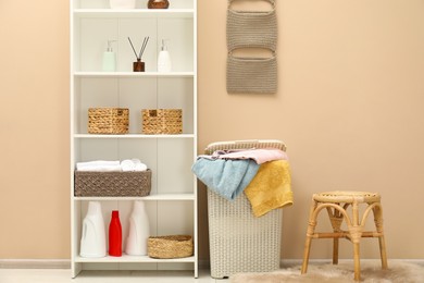 Photo of Wicker basket full of laundry, detergents and toiletries in bathroom