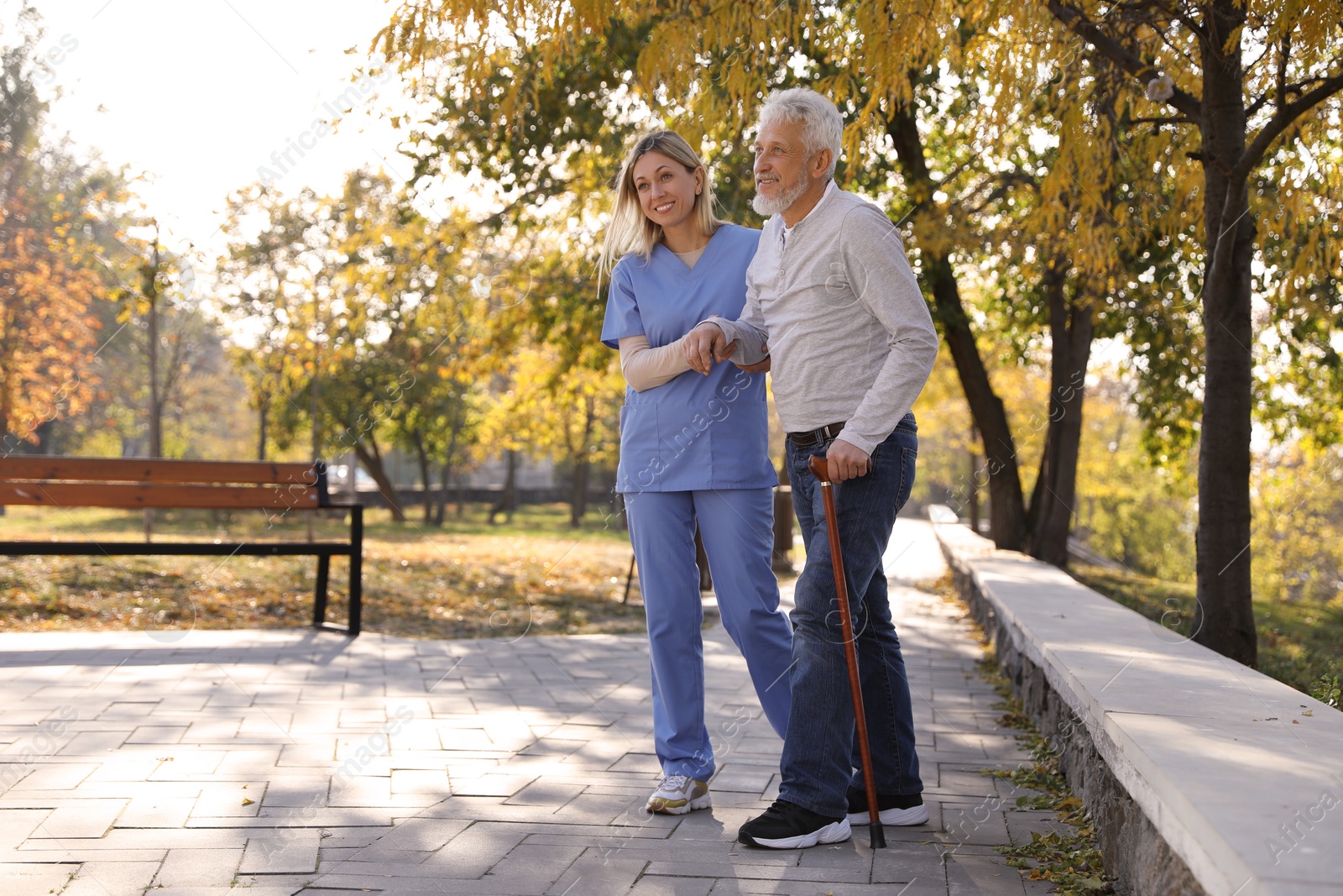 Photo of Caregiver assisting senior man in park. Home health care service