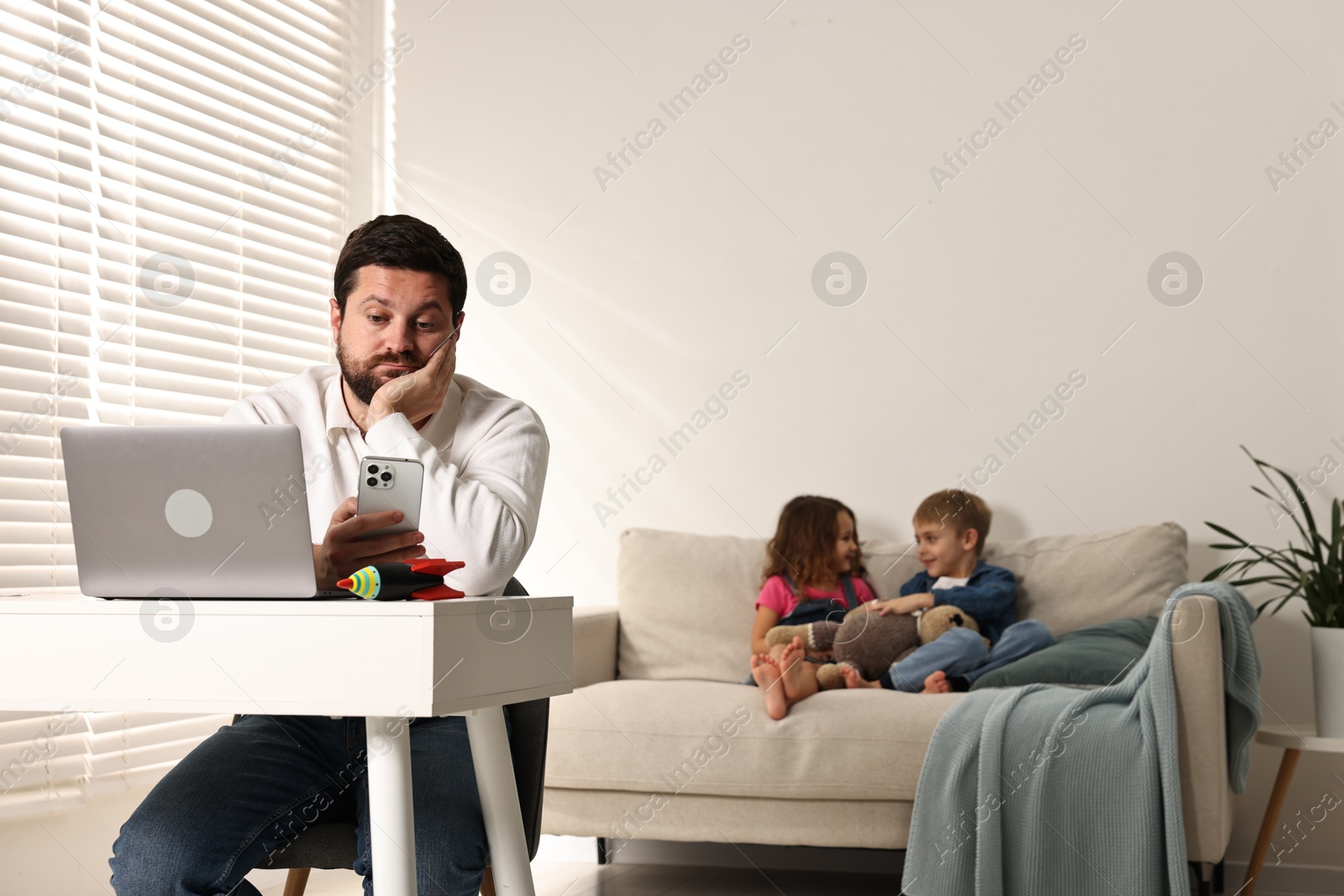 Photo of Naughty children disturbing their overwhelmed father at home