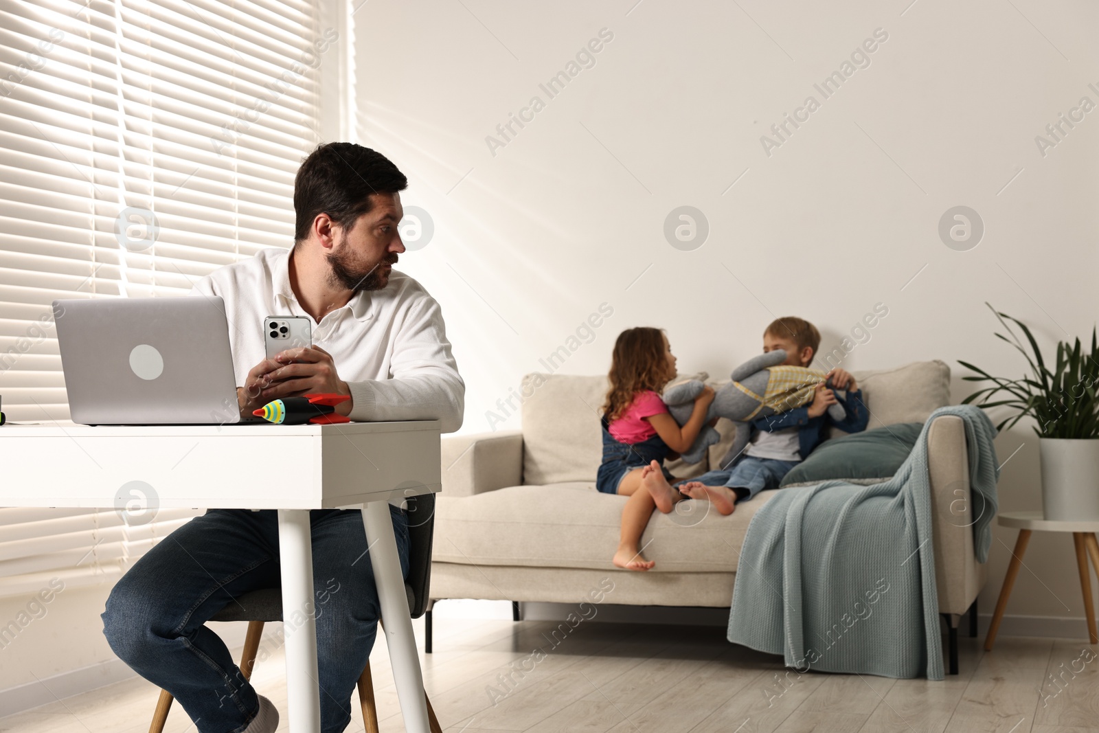 Photo of Naughty children disturbing their overwhelmed father at home