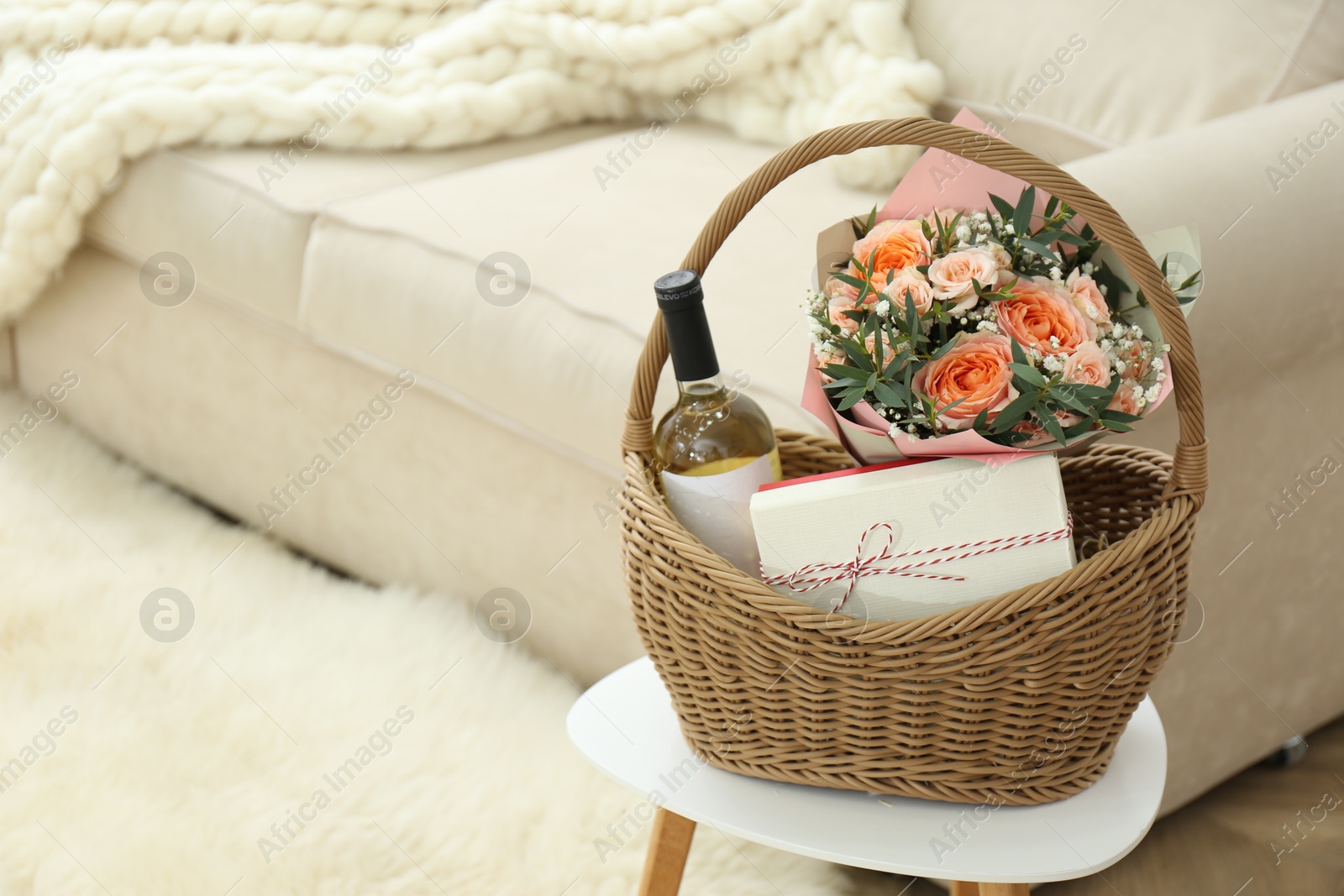 Photo of Wicker basket with gifts on table indoors. Space for text