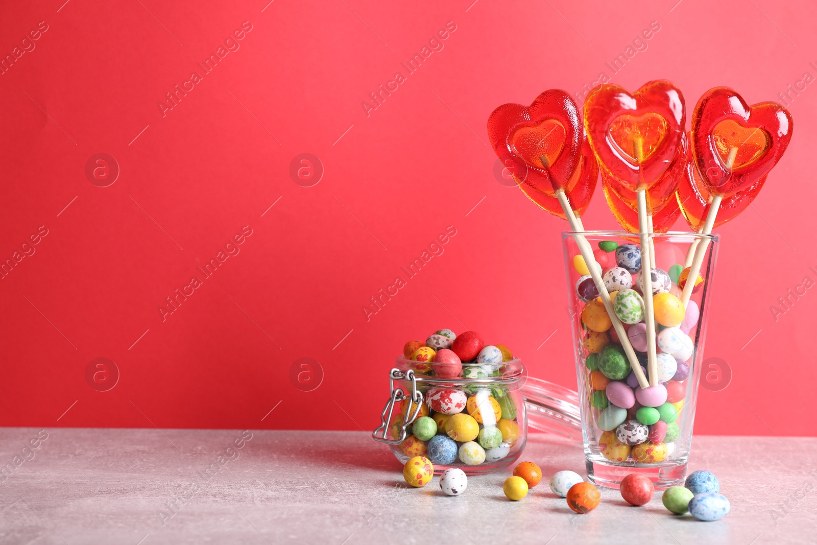 Photo of Delicious heart shaped lollipops and dragees on table. Space for text