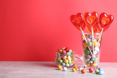 Photo of Delicious heart shaped lollipops and dragees on table. Space for text