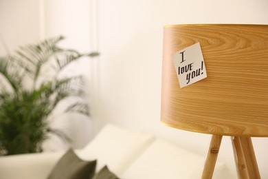 Photo of Paper note with handwritten words I Love You on lamp in living room. Space for text