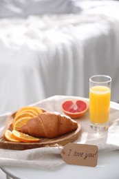 Photo of Romantic breakfast with tag saying I Love You on table in bedroom