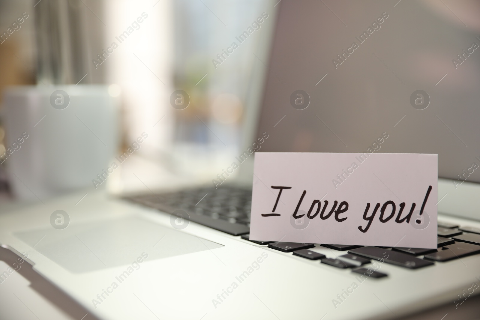 Photo of Note with handwritten text I Love You on laptop. Romantic message