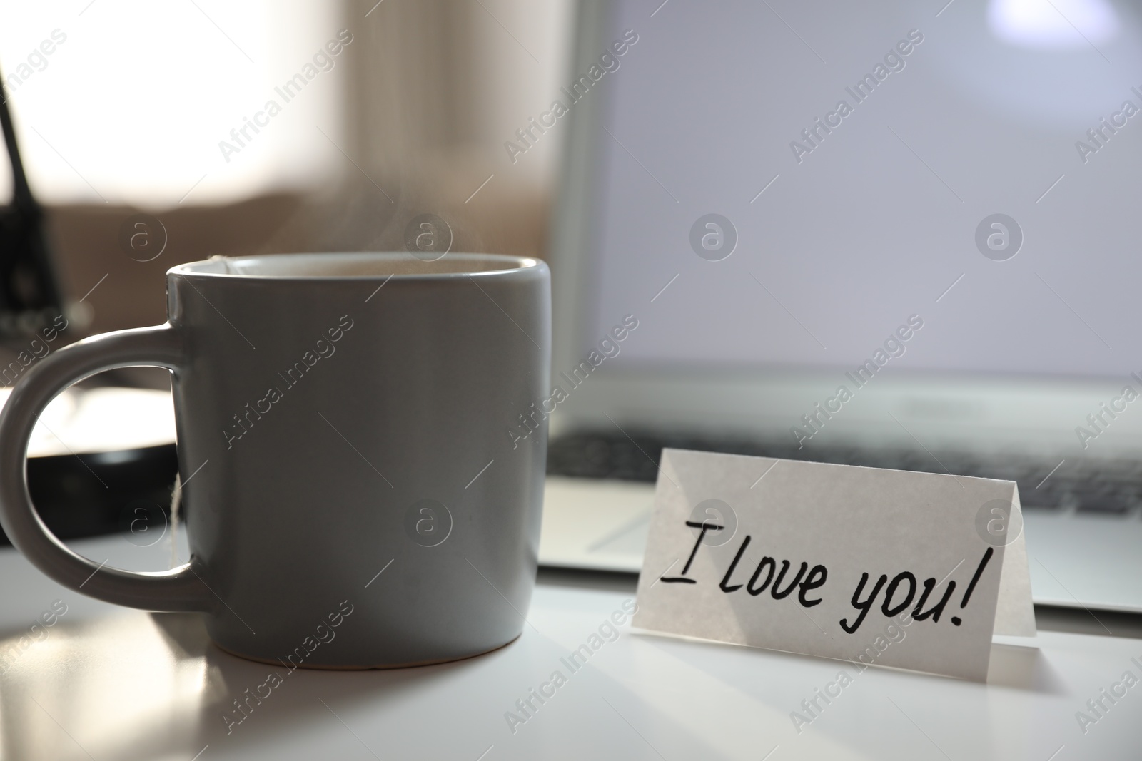 Photo of Note with handwritten text I Love You on workplace. Romantic message