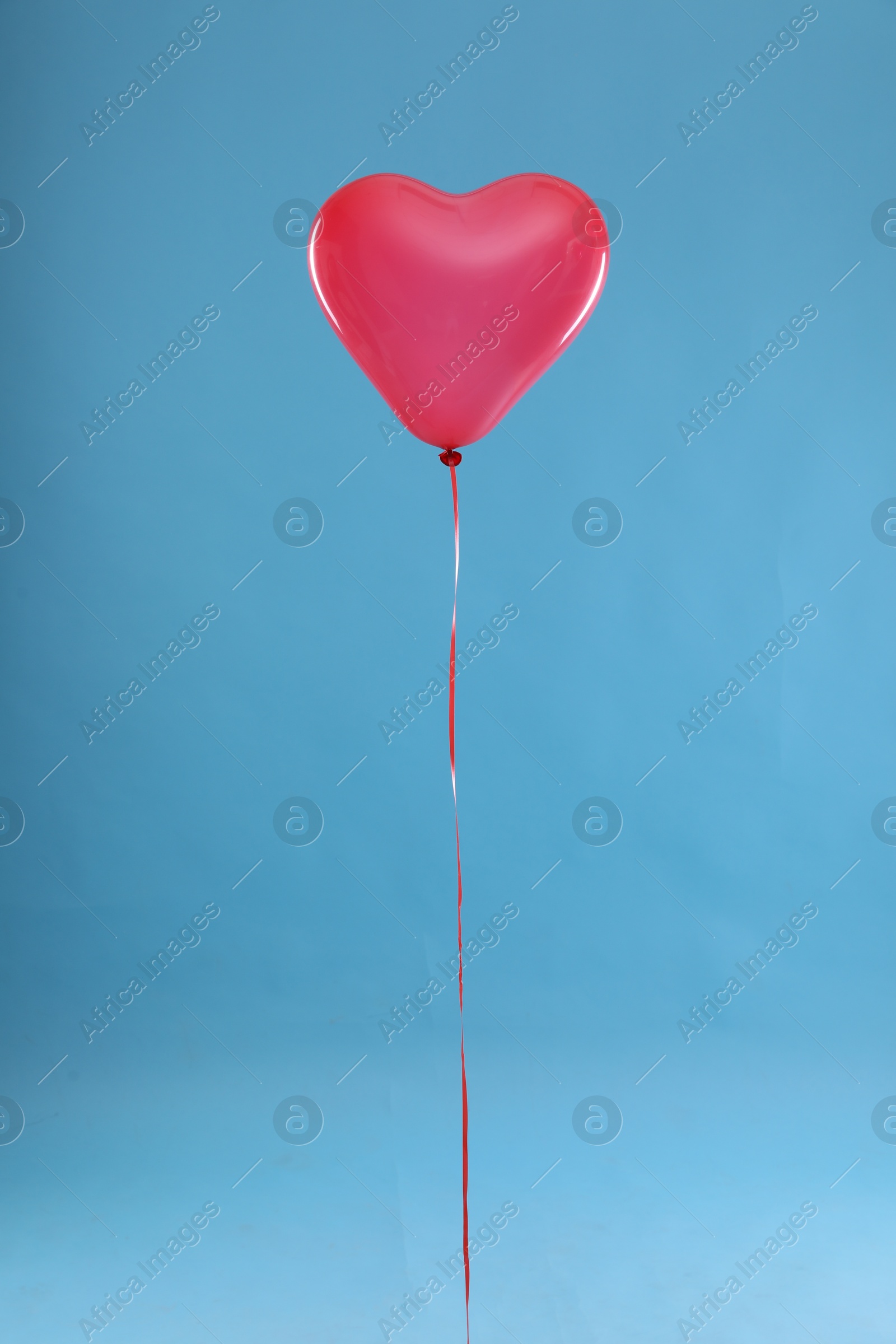 Photo of Festive heart shaped balloon on light blue background