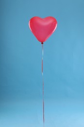 Photo of Festive heart shaped balloon on light blue background