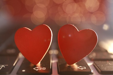 Photo of Decorative hearts on laptop keyboard, closeup. Online dating concept