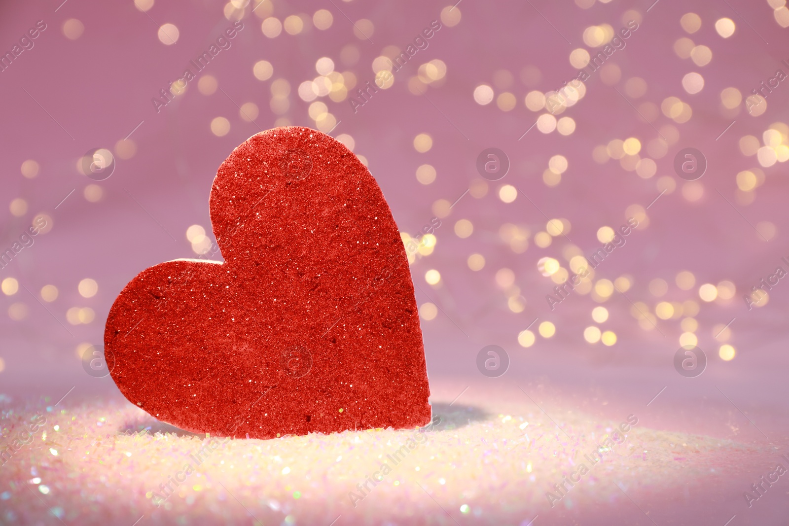 Photo of Red decorative heart on glitter against blurred lights, closeup