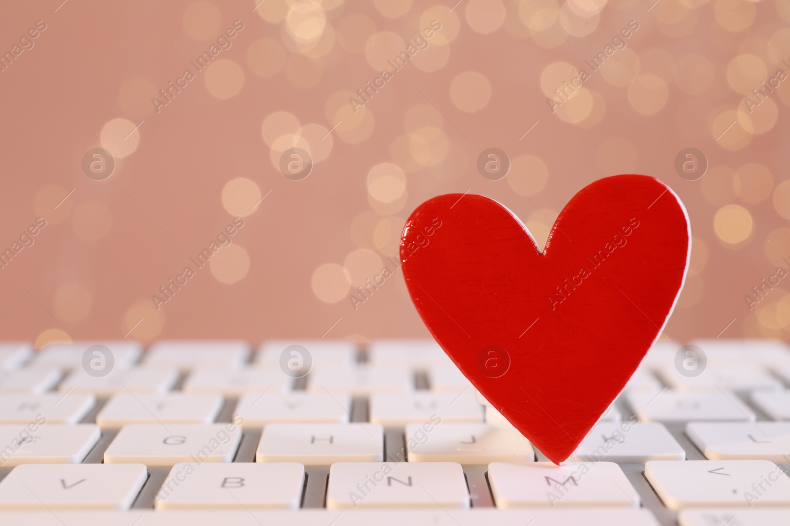 Photo of Red decorative heart on laptop keyboard, closeup. Online dating concept