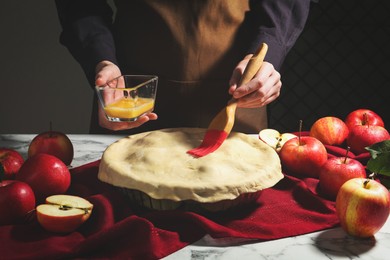 Photo of Woman making homemade apple pie at white marble table, closeup