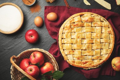 Photo of Flat lay composition with tasty homemade apple pie and ingredients on dark textured table