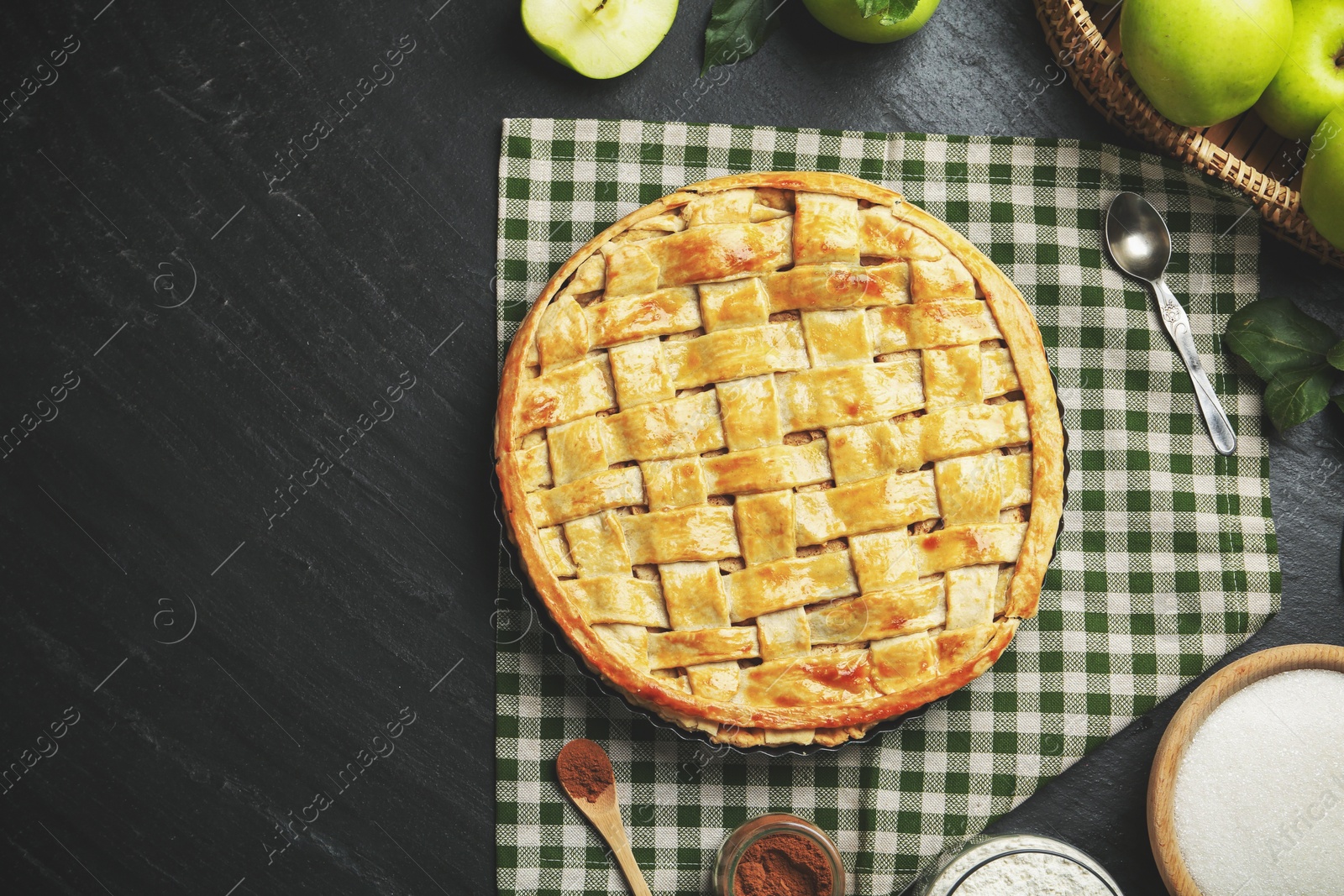 Photo of Flat lay composition with tasty homemade apple pie and ingredients on dark textured table. Space for text