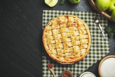 Photo of Flat lay composition with tasty homemade apple pie and ingredients on dark textured table. Space for text