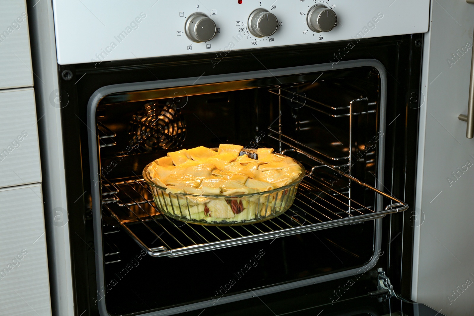 Photo of Baking dish with raw homemade apple pie in oven