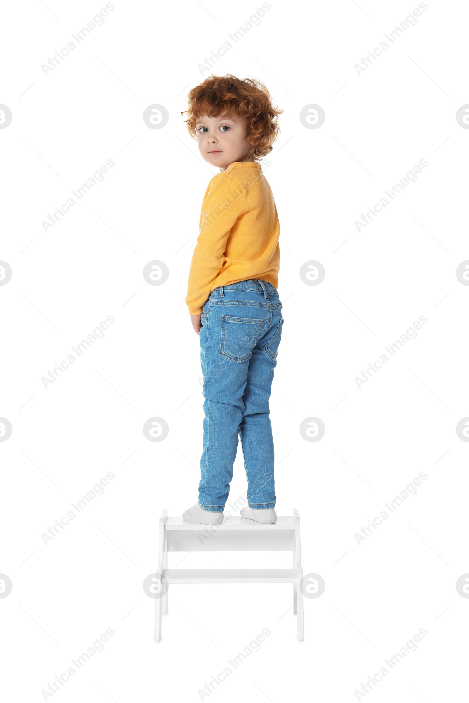 Photo of Little boy standing on step stool against white background