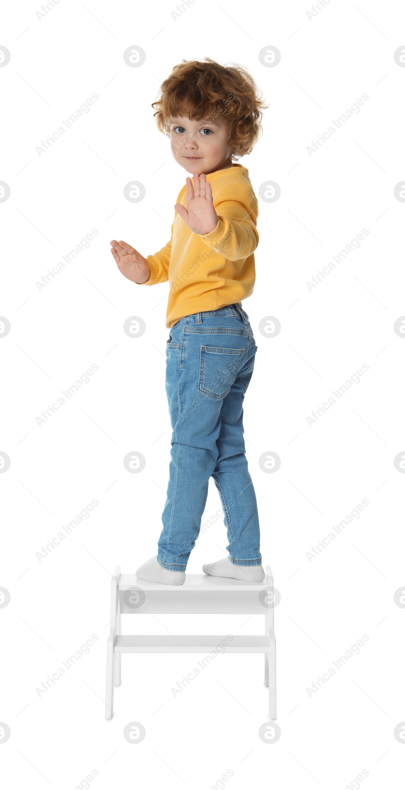 Photo of Little boy standing on step stool against white background