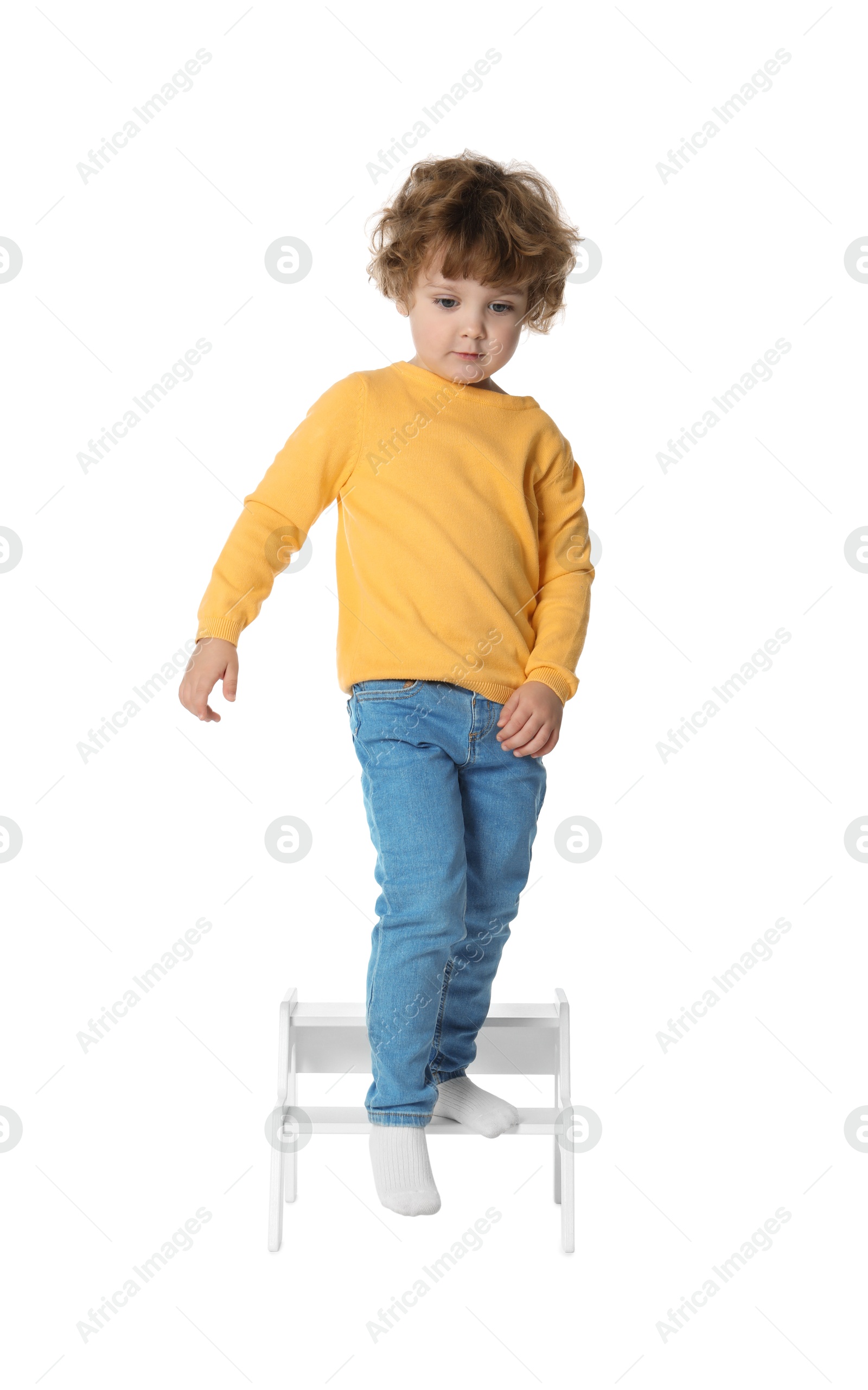 Photo of Little boy standing on step stool against white background