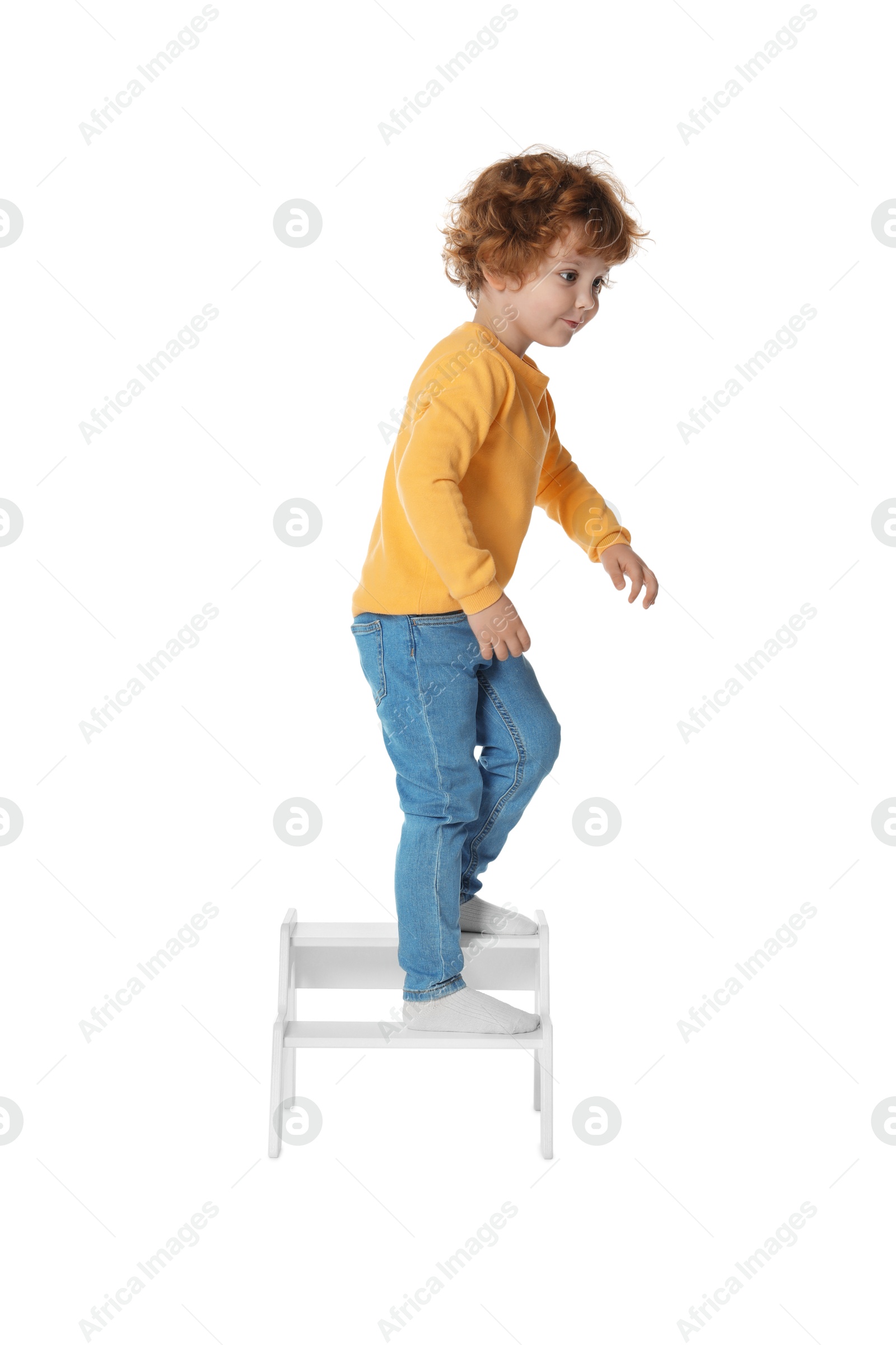 Photo of Little boy standing on step stool against white background