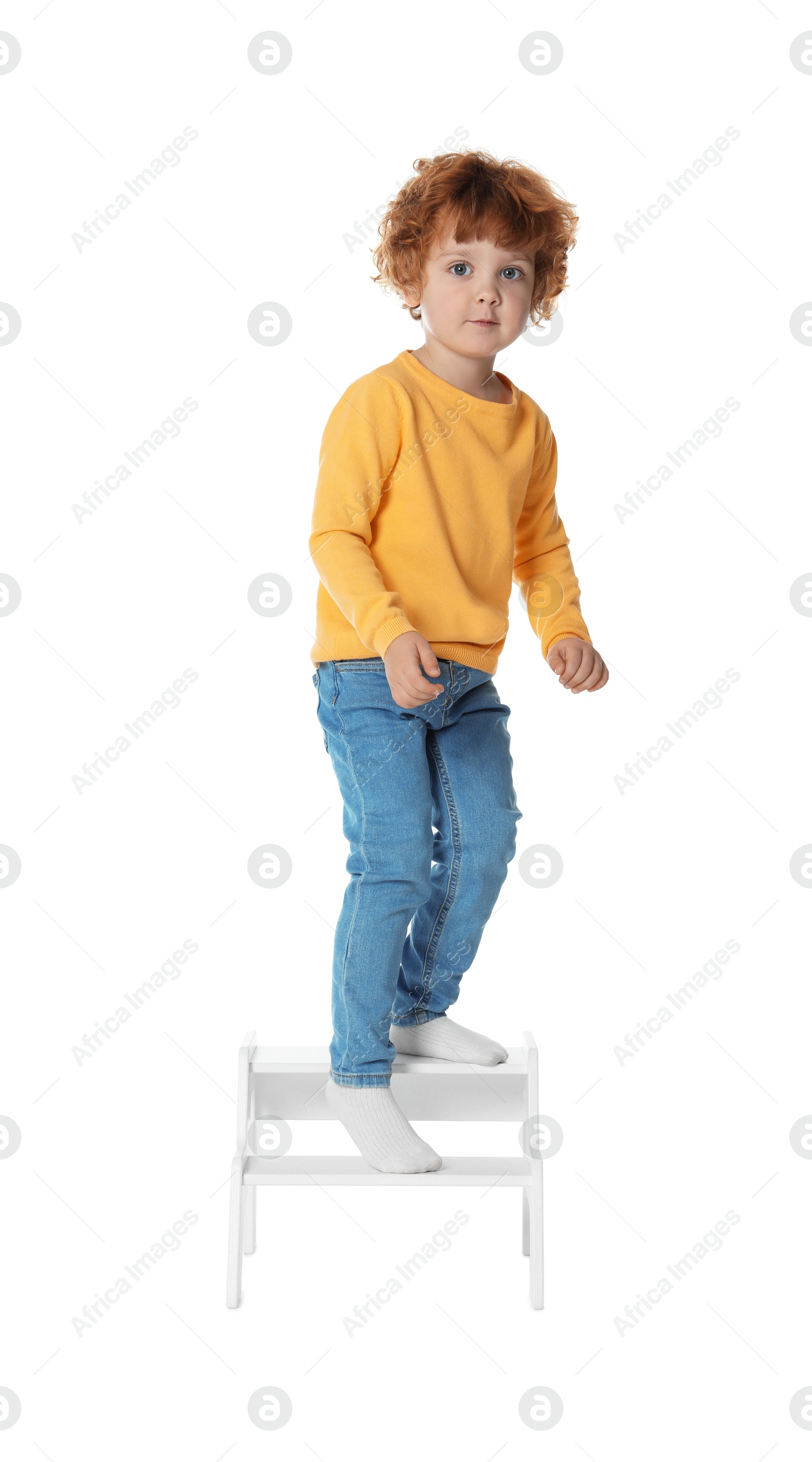 Photo of Little boy standing on step stool against white background