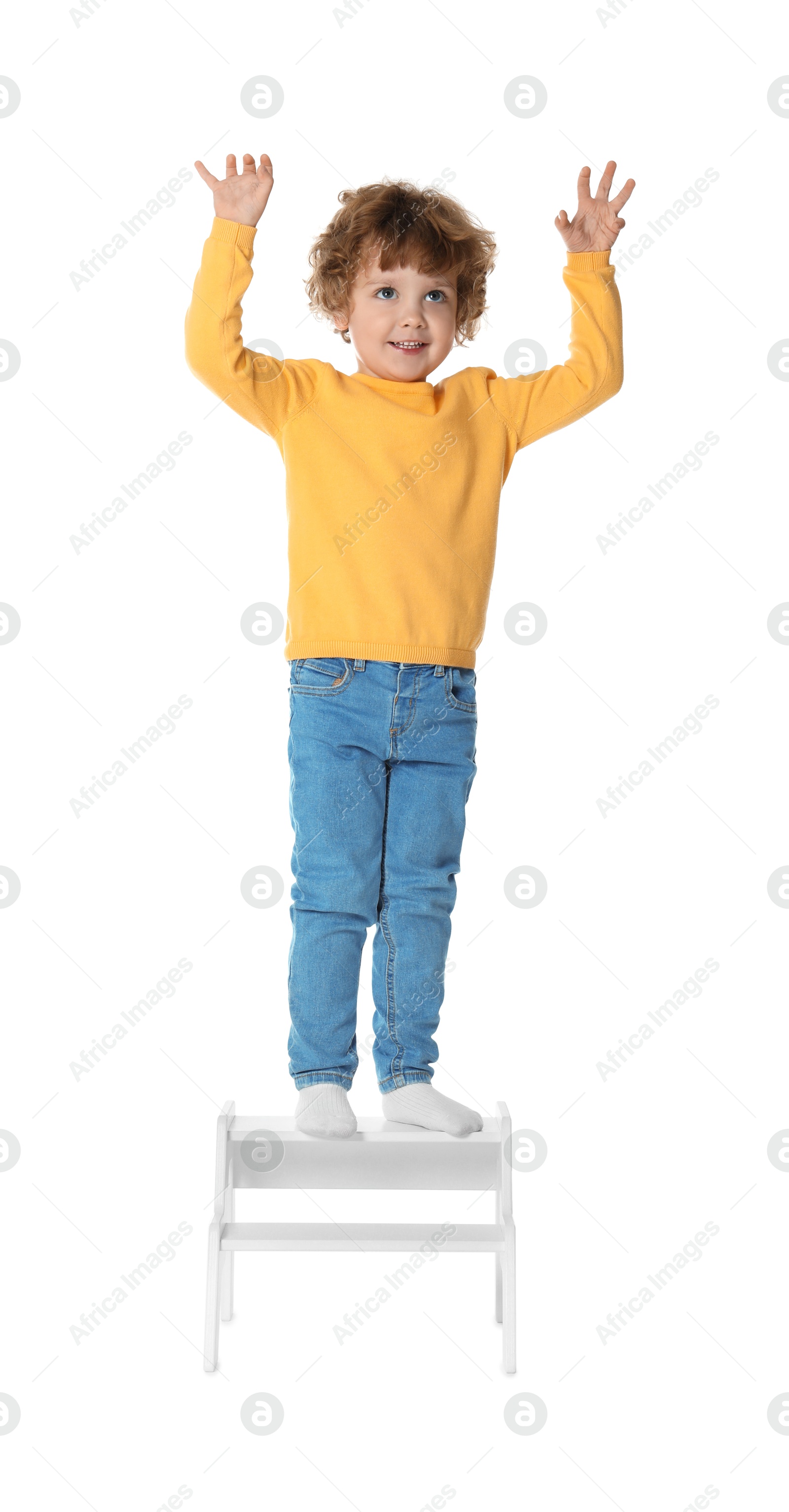 Photo of Little boy standing on step stool against white background