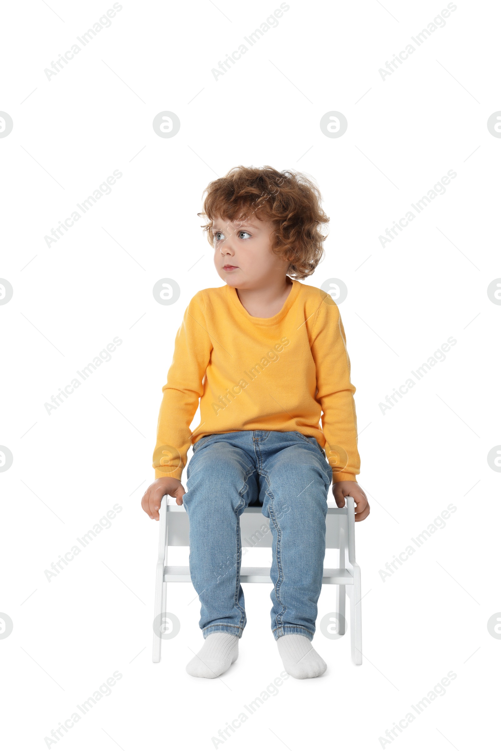 Photo of Little boy sitting on step stool against white background